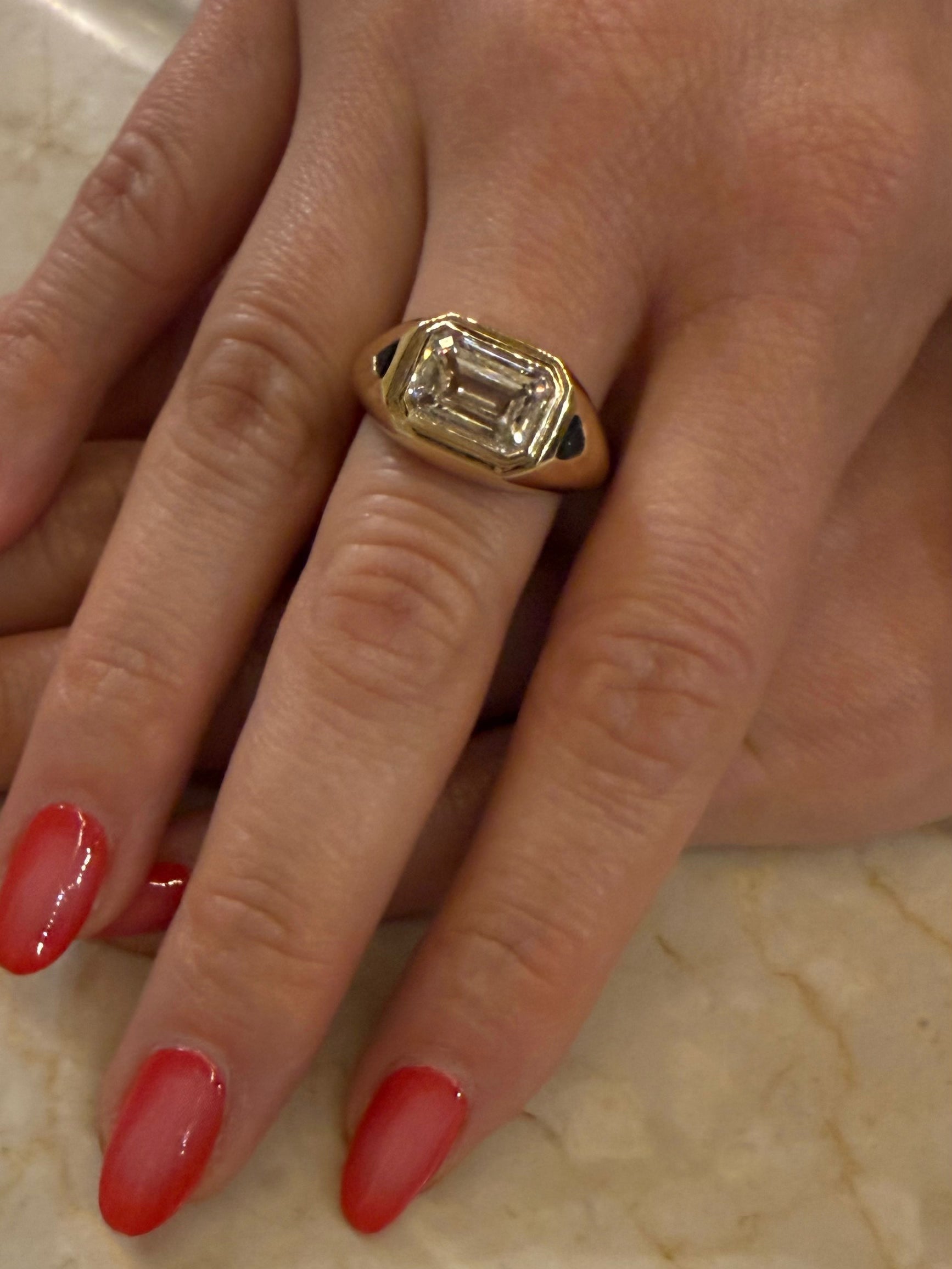 Model wearing the Femme Forte emerald-cut diamond signet ring in yellow gold with green side stones