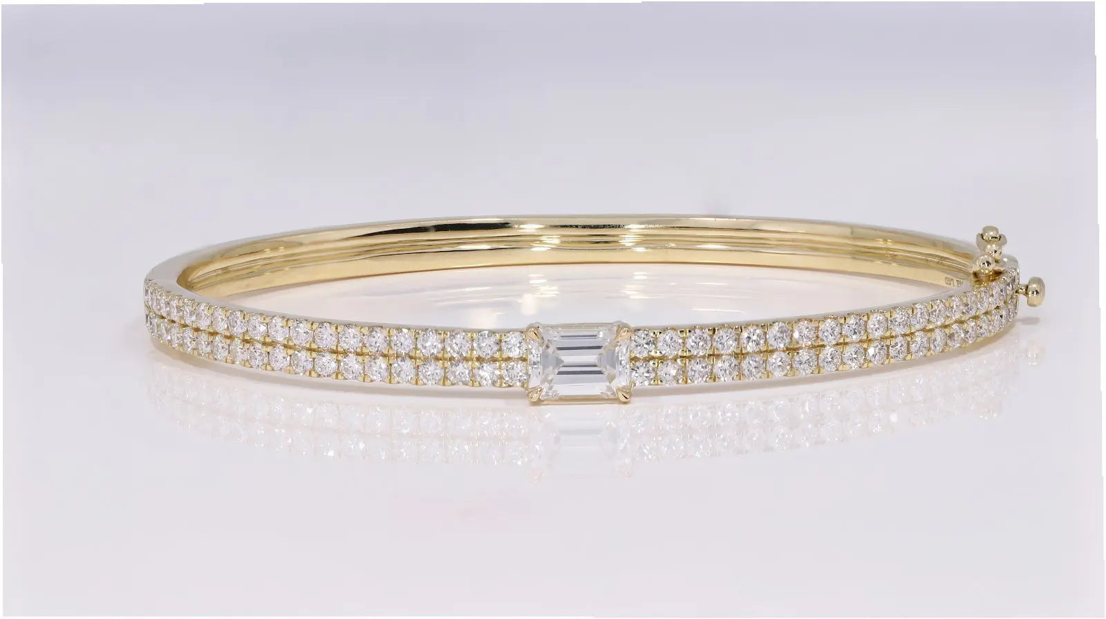 The Clarity Bangle in yellow gold showcasing emerald-cut diamond and sustainable pavé accents, front-facing view with interior visible