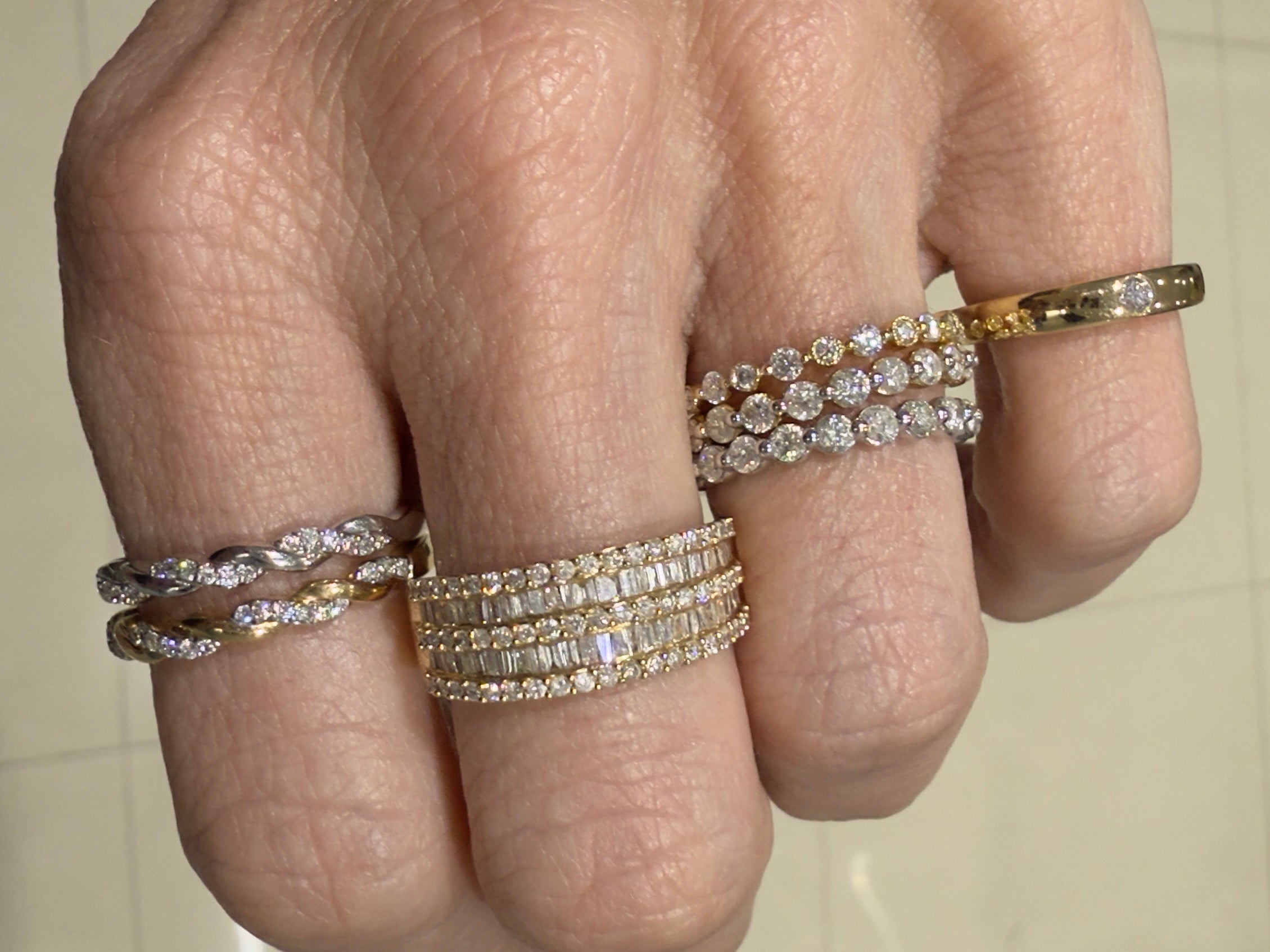 Close-up editorial image of a hand with stacked diamond rings including the Double Trouble Pavé x Baguette Ring.
