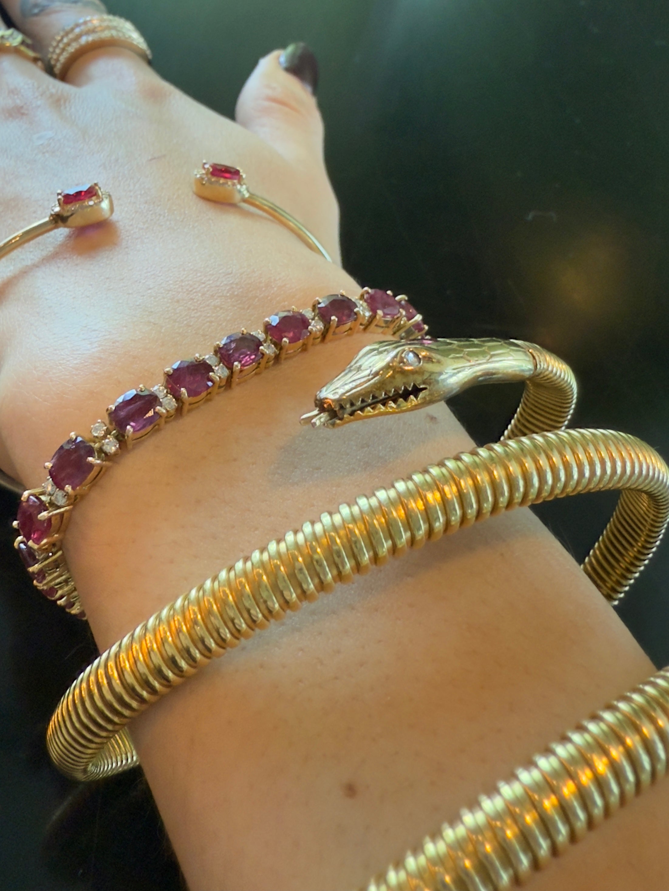 Heaven Sent tennis bracelet and Snake wrap bangle styled with other gold bangles on a wrist, emphasizing color and texture variety.