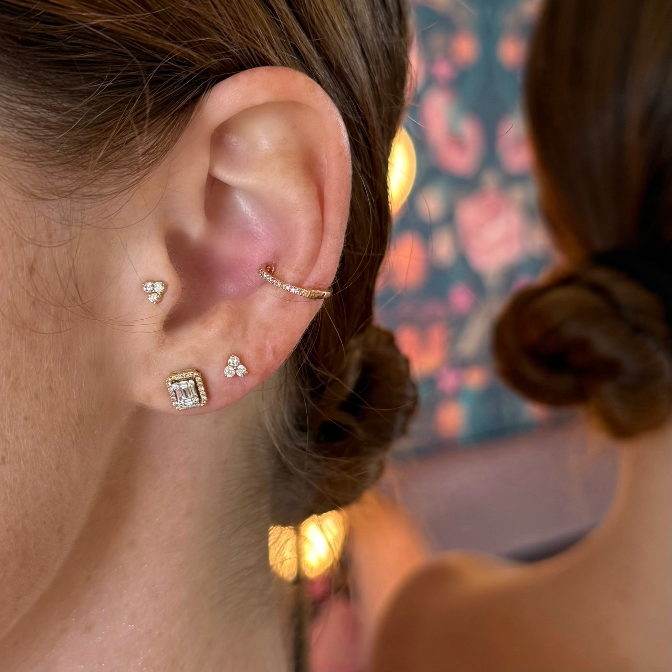 Model wearing Hold My Halo diamond illusion emerald stud and Politely Petite Trio Stud earrings