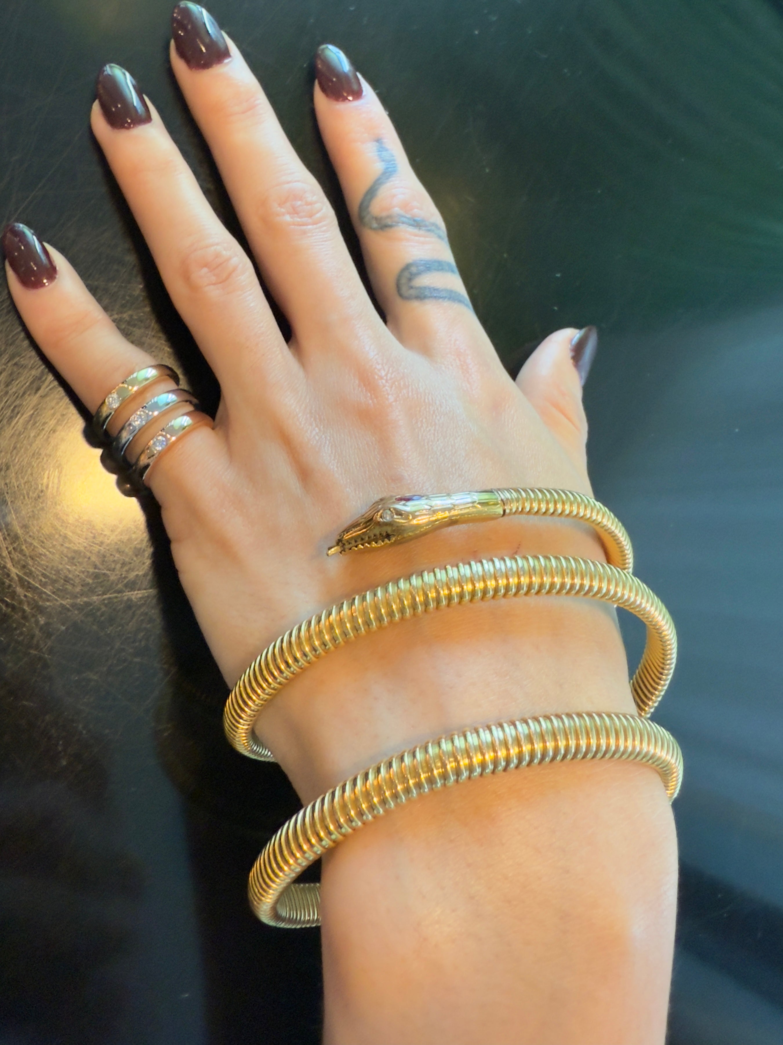 Close-up of 14k gold Snake Wrap Bangle on hand, showcasing serpent-inspired design with ruby-set head and diamond eyes