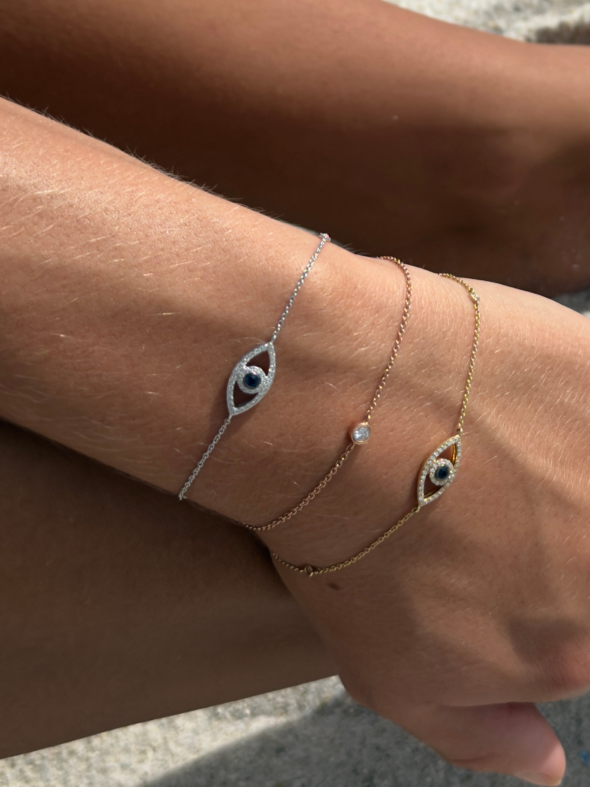 Close-up of wrist stack with Samba No Pé bracelet and Watchful Eye Bracelet in white and yellow gold