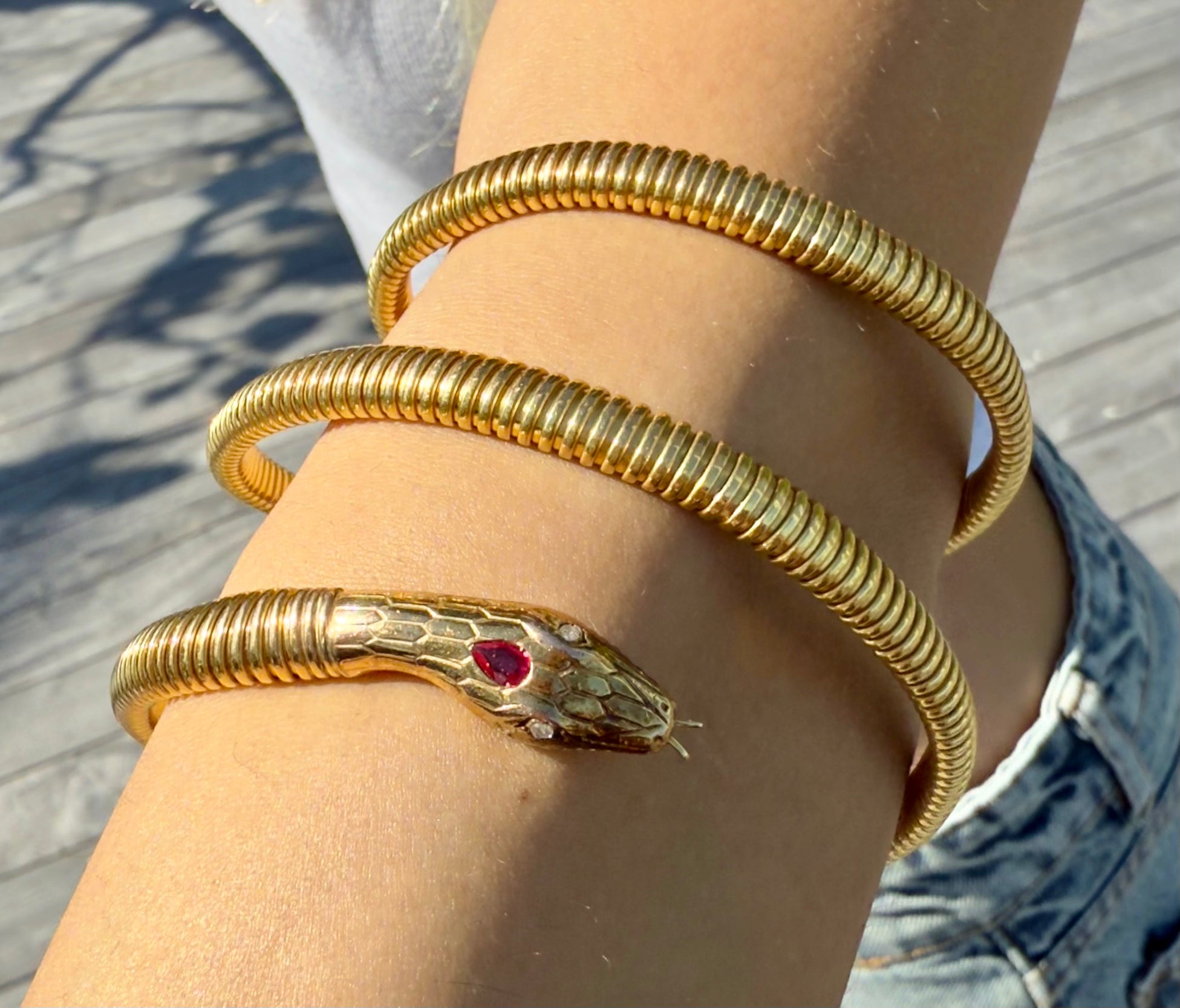 We Are One Snake Wrap Bangle worn solo on the arm, showing sleek gold serpent design with ruby and diamond accents