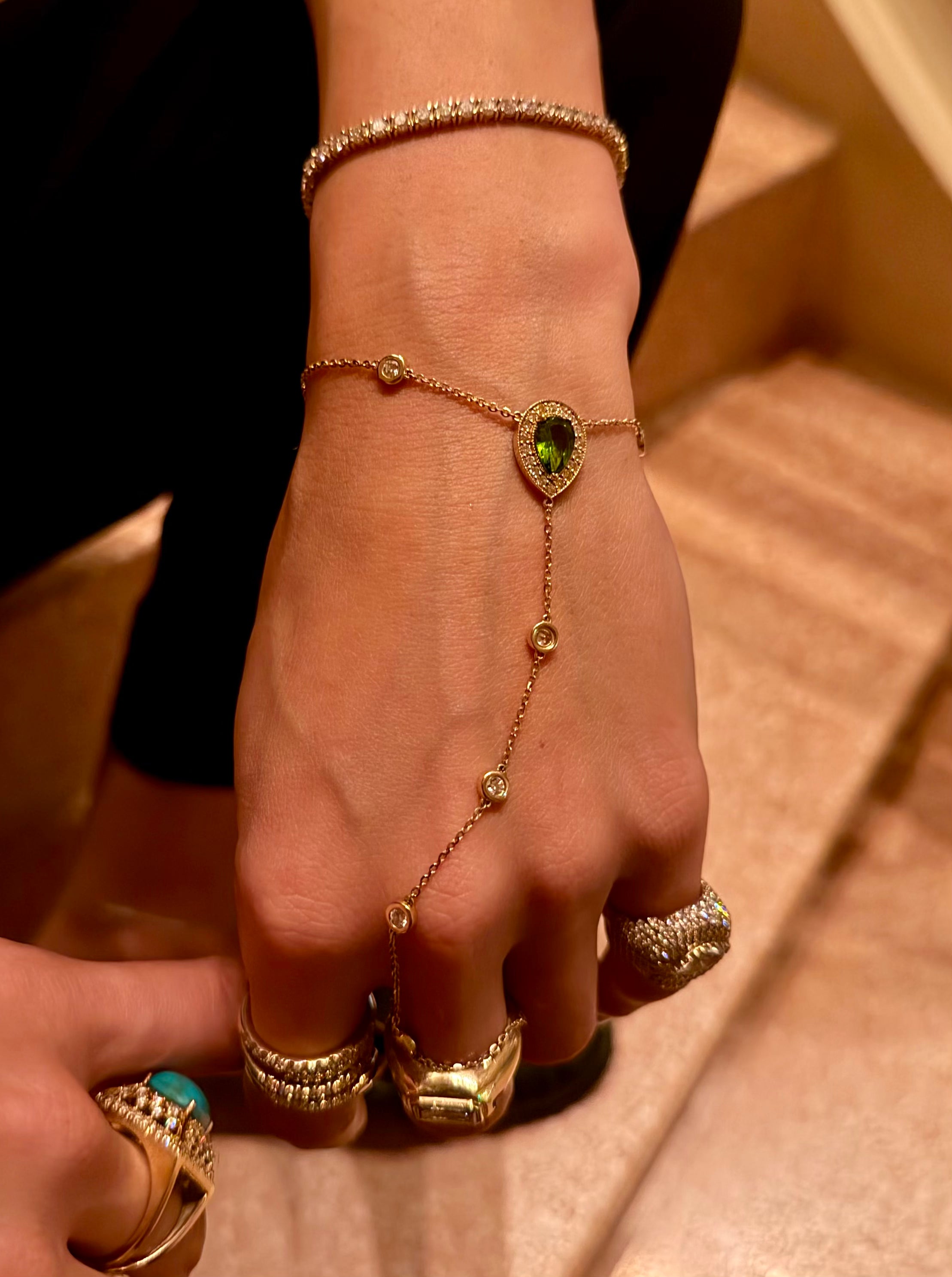 Boheme hand chain in yellow gold and peridot center stone pear cut surrounded by diamonds styled on hand