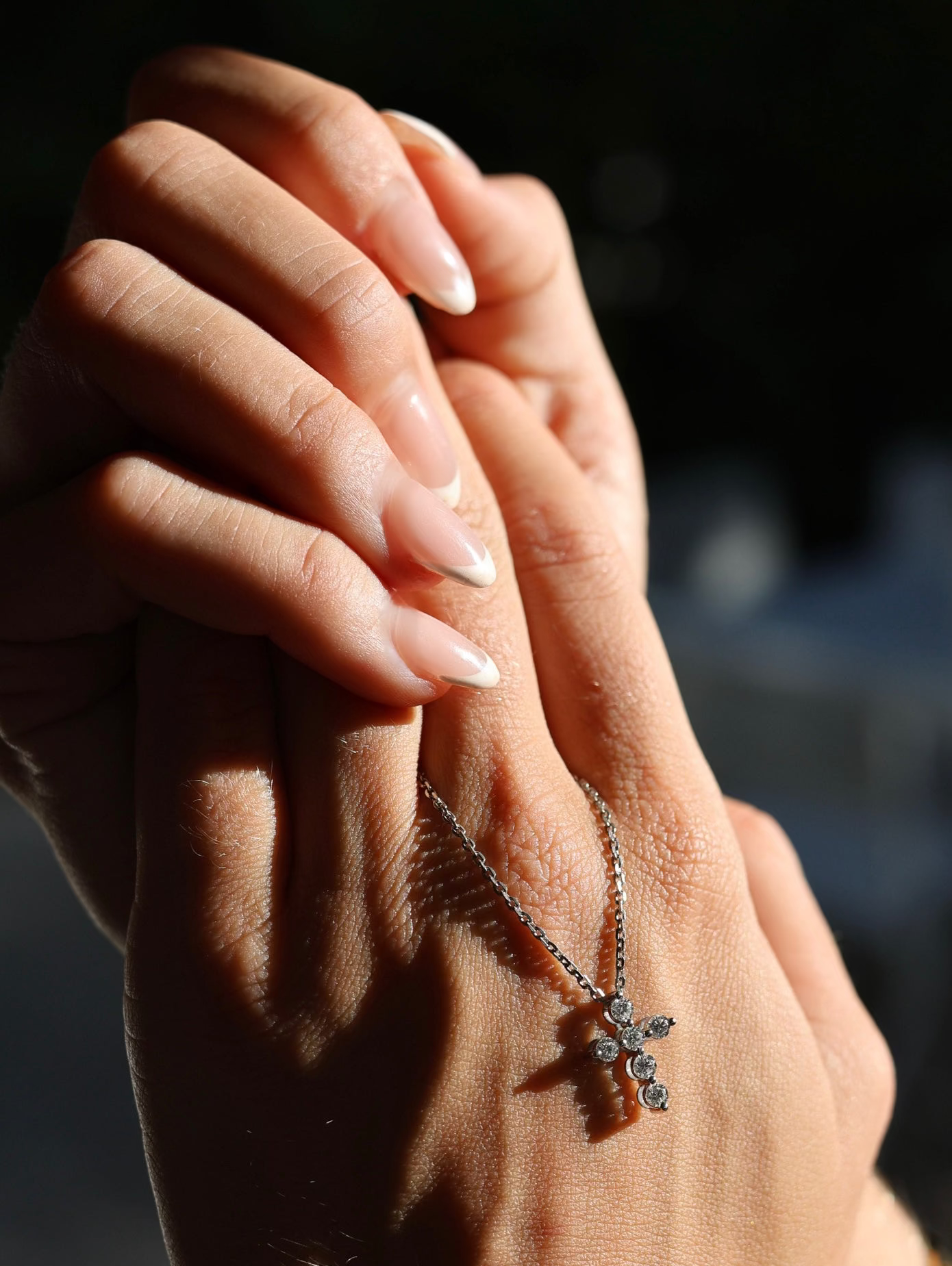 Fromm Gods love diamond cross pendant in white gold resting on a hand