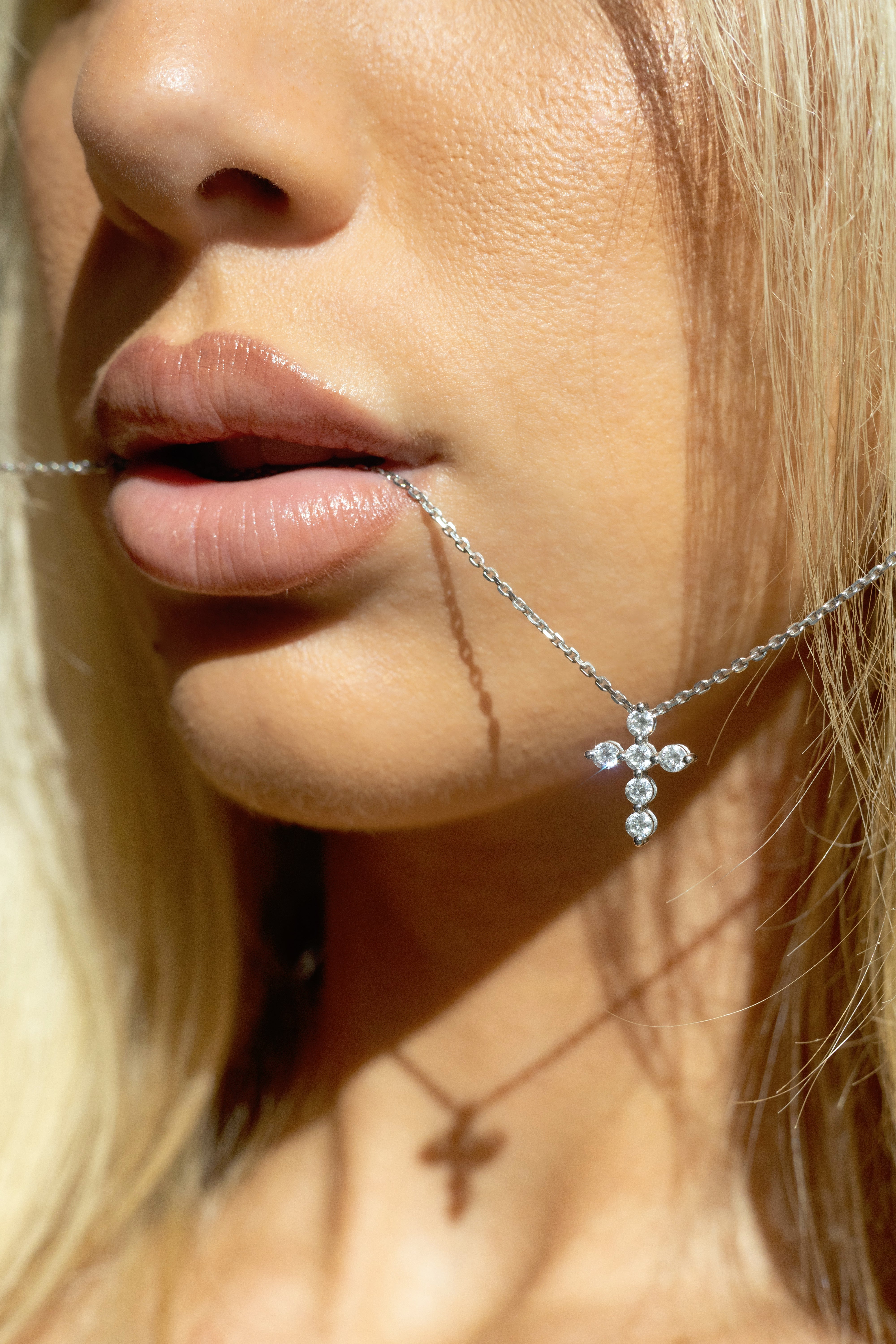 Photo of the Fromm Gods love diamond cross pendant hanging from models mouth