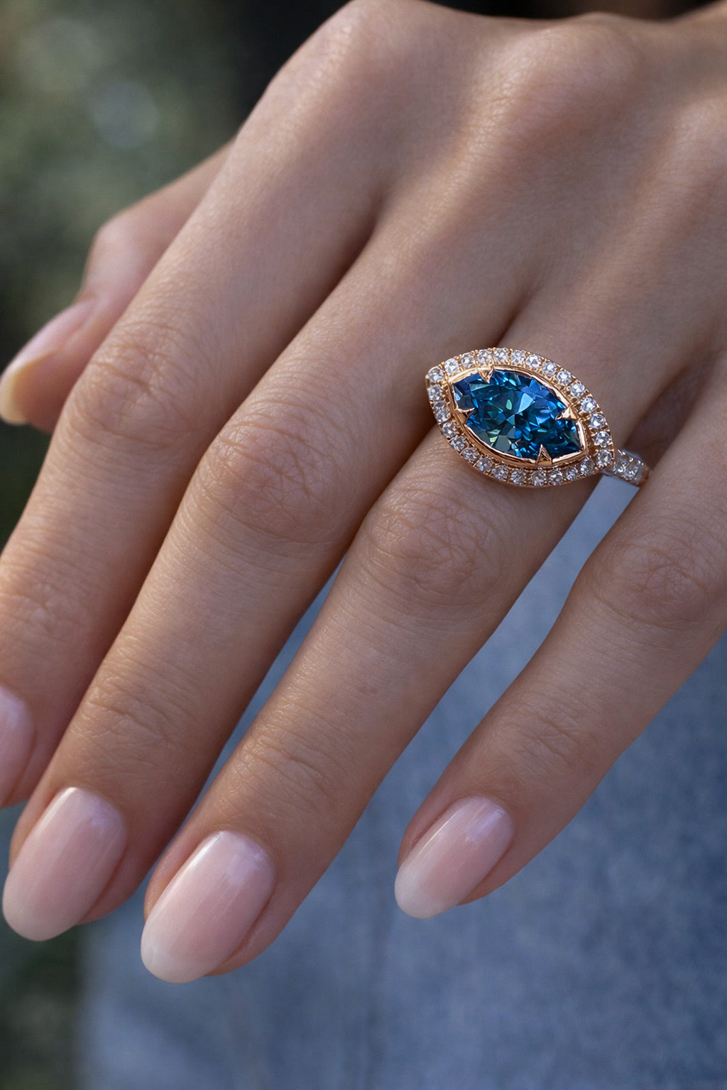 Ocean Eye Halo ring with marquise cut blue diamond center stone surrounded by diamond halo on models hand — Waltz Diamonds