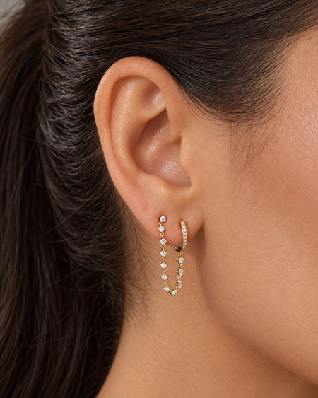 Plus one diamond chain huggie is designed for two piericngs and connects a diamond huggie with a chain of diamonds to another in yellow gold on ear — Waltz Diamonds
