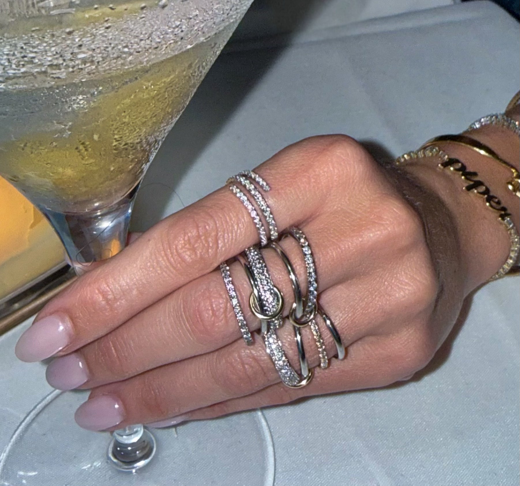 Close up of the two different styles of the Quintet ring featuring 5 silver bands linked by small gold bands with pave diamonds—Waltz Diamonds