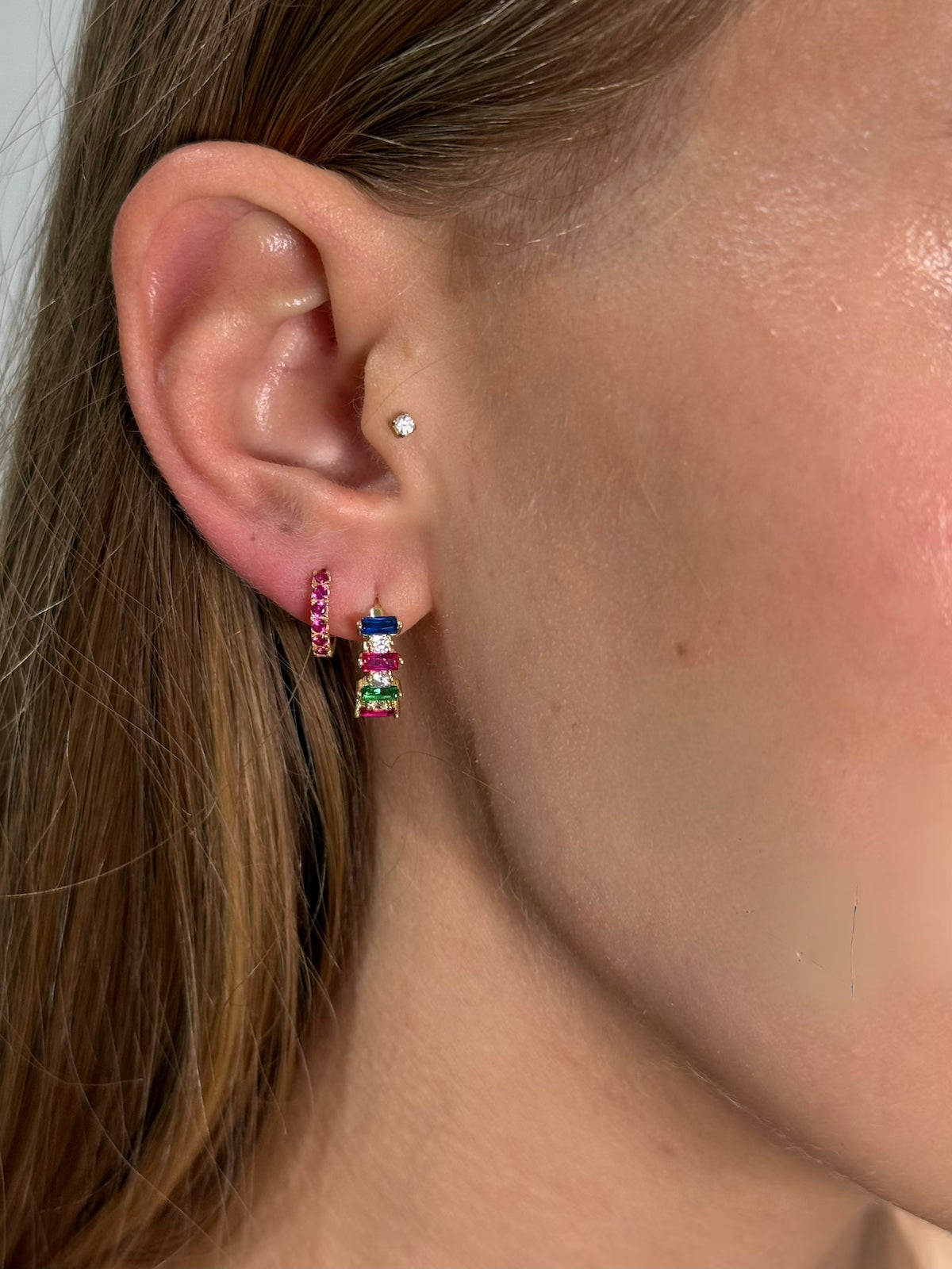 Rainbow gem huggies and color-pop-huggies styled on models ear — Waltz Diamonds