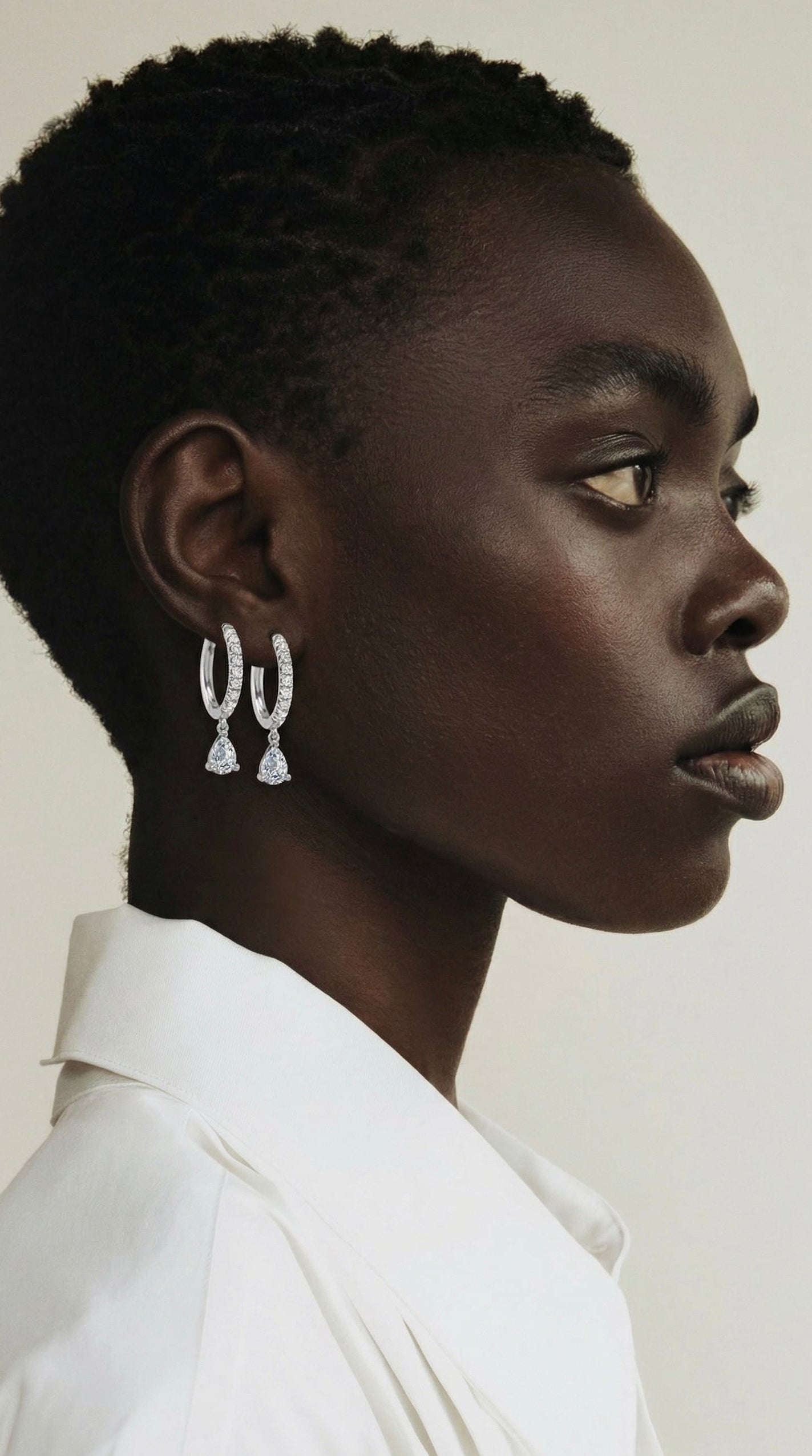 Unhinged huggies featuring a pavé hoop with a drop diamond in white gold on model Waltz Diamonds