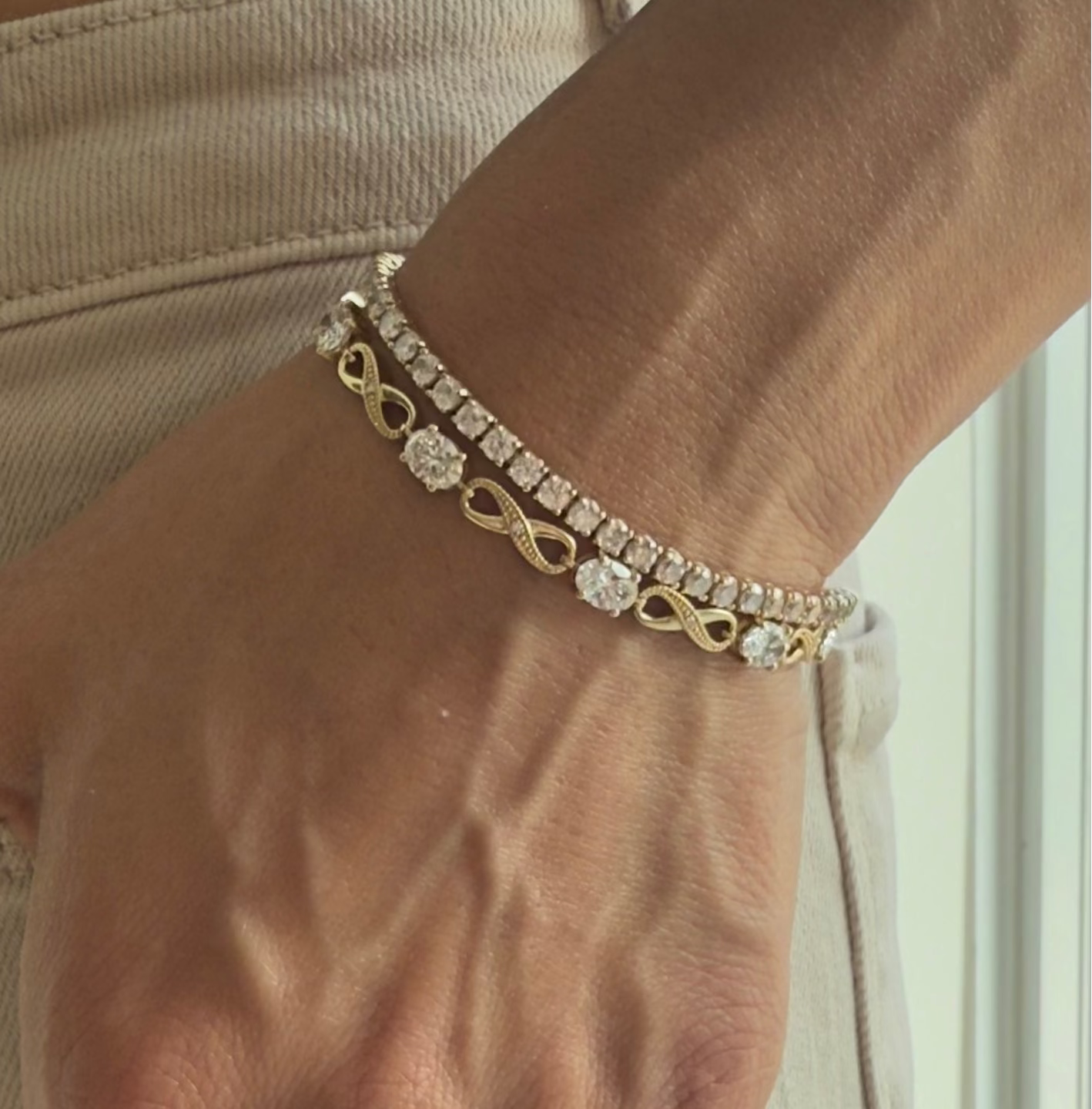 Hand wearing the abundance bracelet and Spoil Me  tennis bracelet in yellow gold, styled with rings and bracelets from Waltz Diamonds