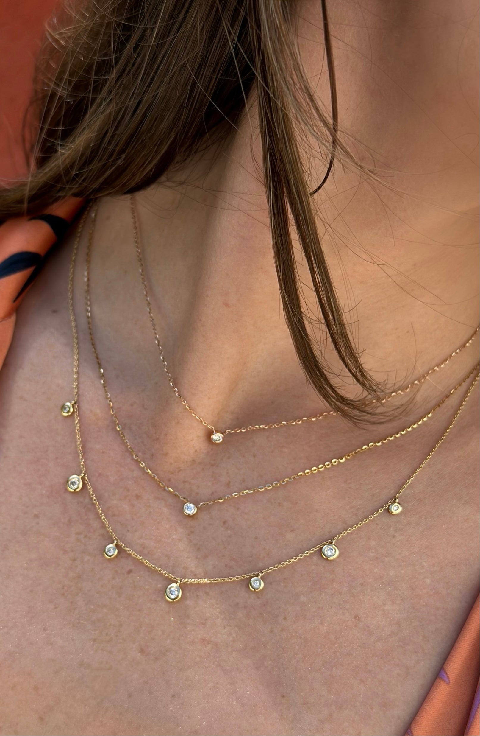 Baby Bezel Petite Diamond Necklace styled with Dirty Dancing Bezeled Diamond Necklace stacked gold necklaces on model.