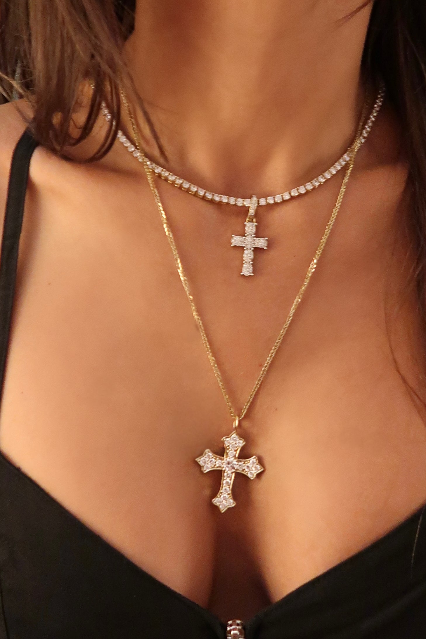 Model wearing diamond cross pendant layered with other necklaces for a modern faith-inspired look

