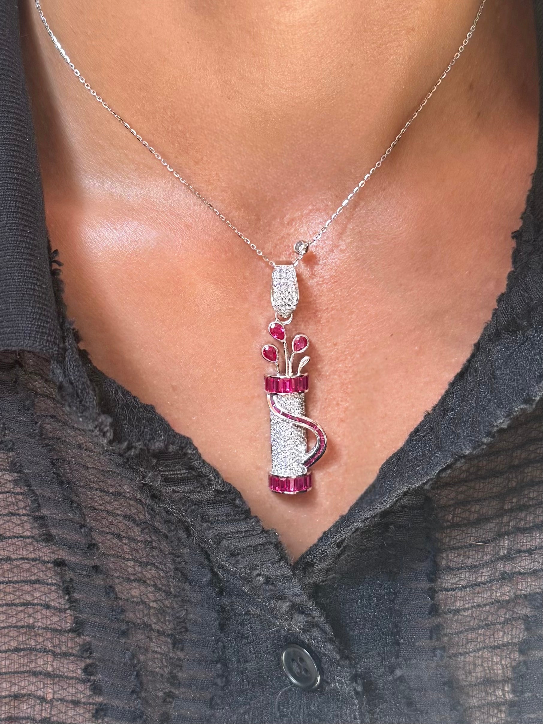 Model wearing Fore Play Pendant featuring diamonds and ruby baguettes in a golf bag charm design