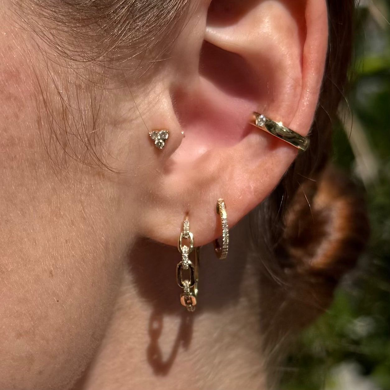Model wearing Forever Yours diamond huggies and Harmless Flirt pavé hoops stacked with other earrings for a layered look