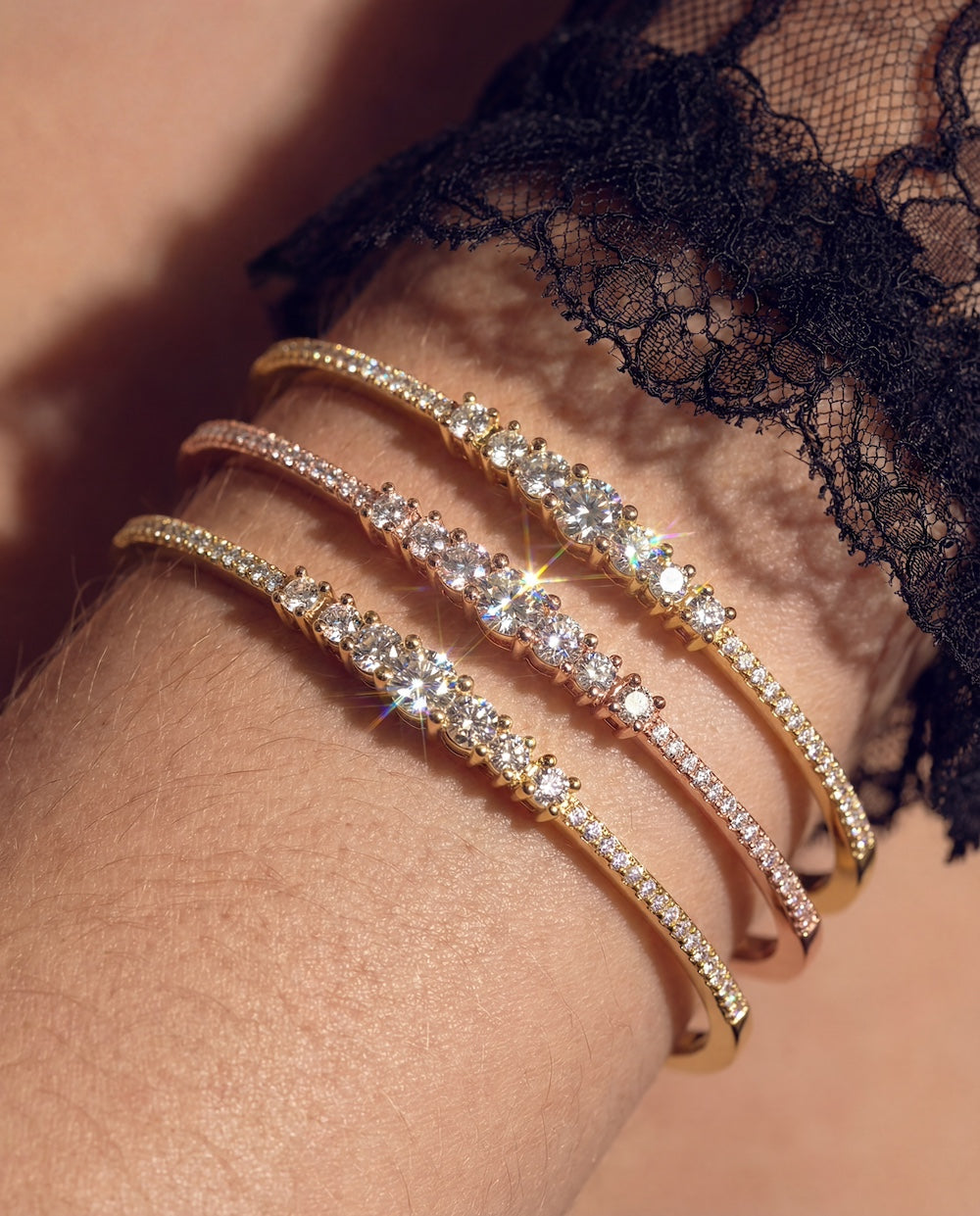 Less s More diamond graduated bangle in yellow gold stacked on models arm —Waltz Diamonds