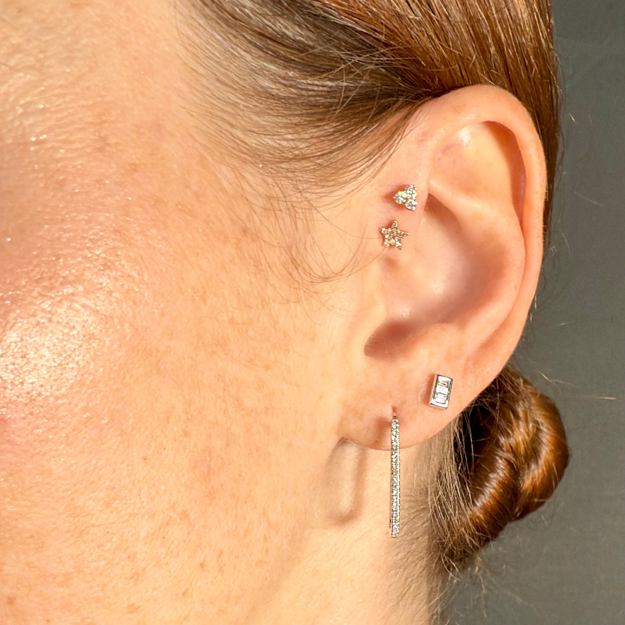 Close-up editorial image of model with Twinkle star stud earrings and Whisper Studs baguette earrings in mixed earring stack