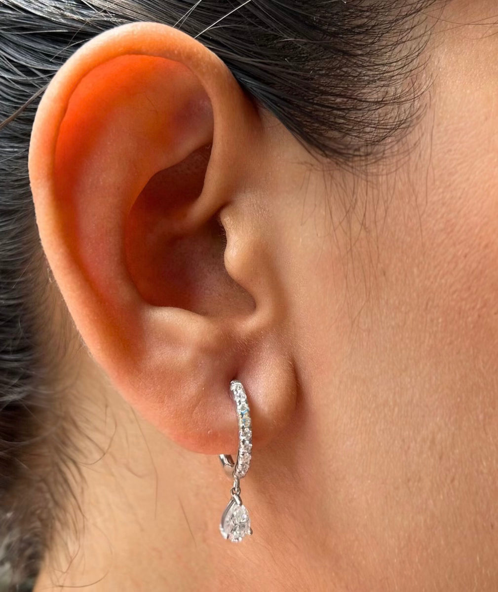 Editorial photo of white gold Unhinged Huggies on model’s ear with suspended diamond drop detail