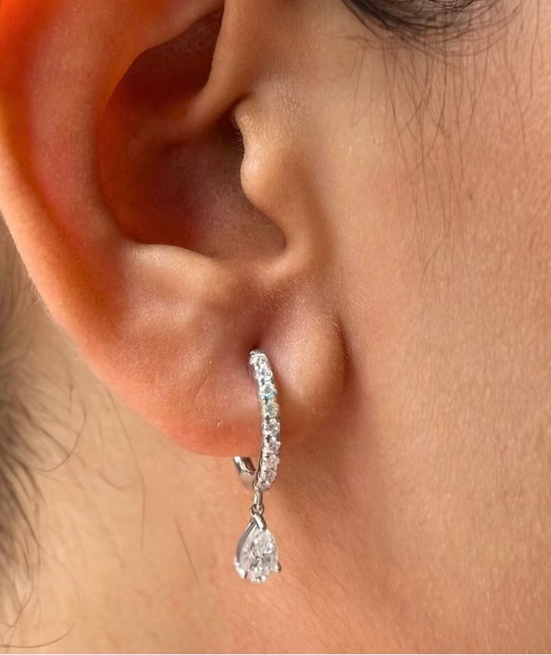 Editorial photo of white gold Unhinged Huggies on model’s ear with suspended diamond drop detail
