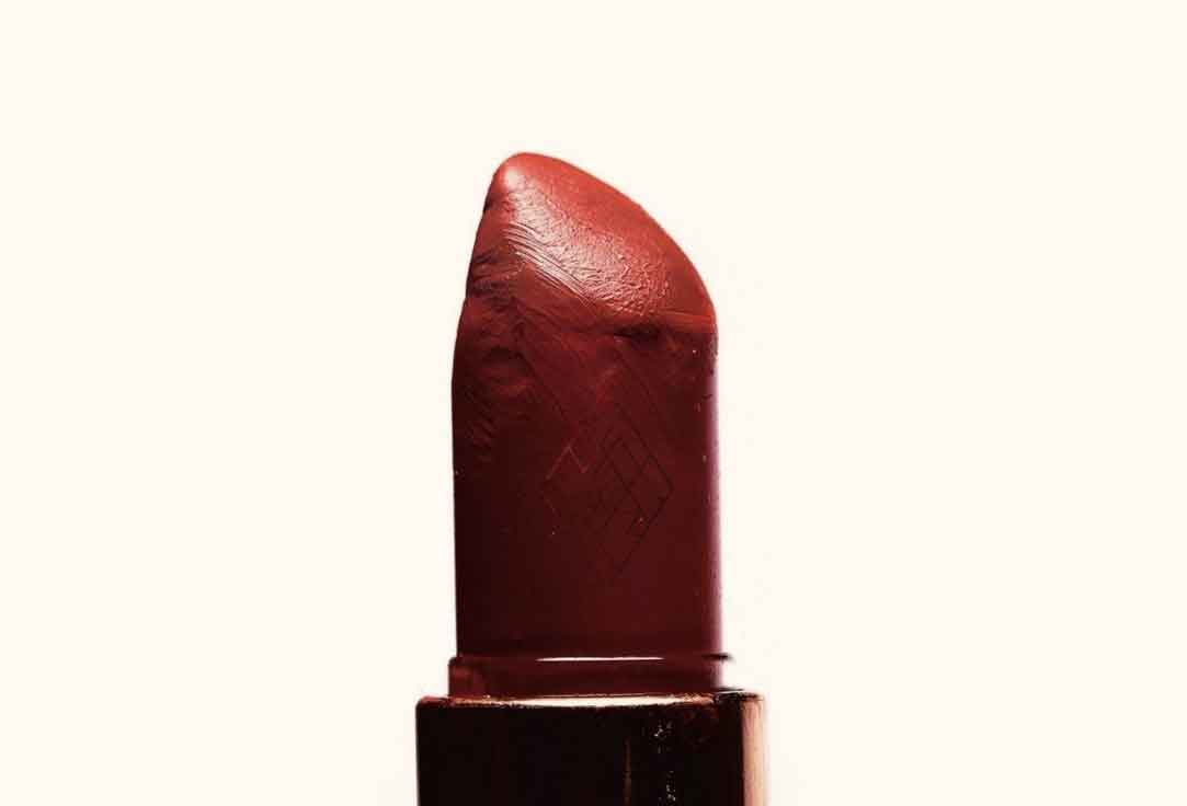 Luxury red lipstick with the Waltz Diamond logo subtly embossed on the lipstick bullet in a detailed close-up shot.